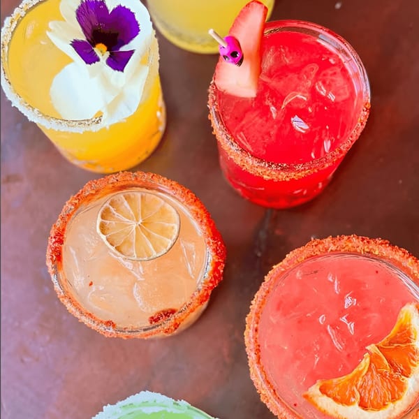 Colorful Hidalgo's Cocina & Cócteles margaritas with fruit garnishes and chili-lime rims.