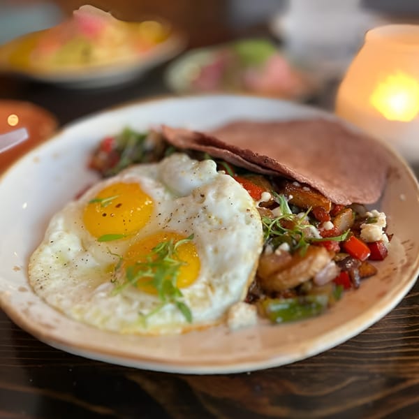 Hidalgo's Cocina & Cócteles' breakfast plate with two fried eggs, potatoes, peppers, and a tortilla.